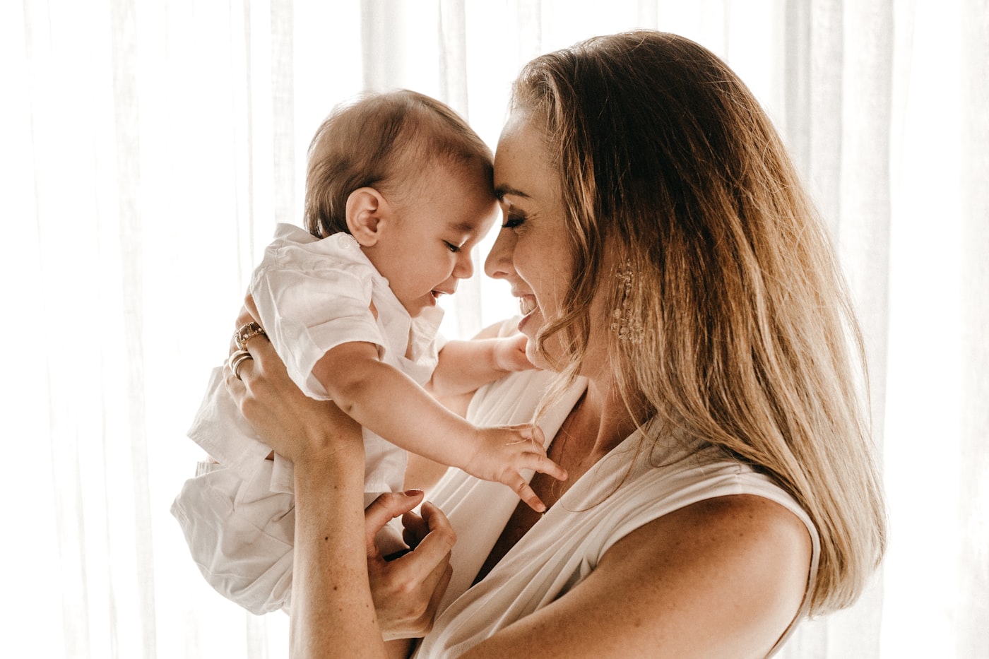 A parent holding a baby in soft window light